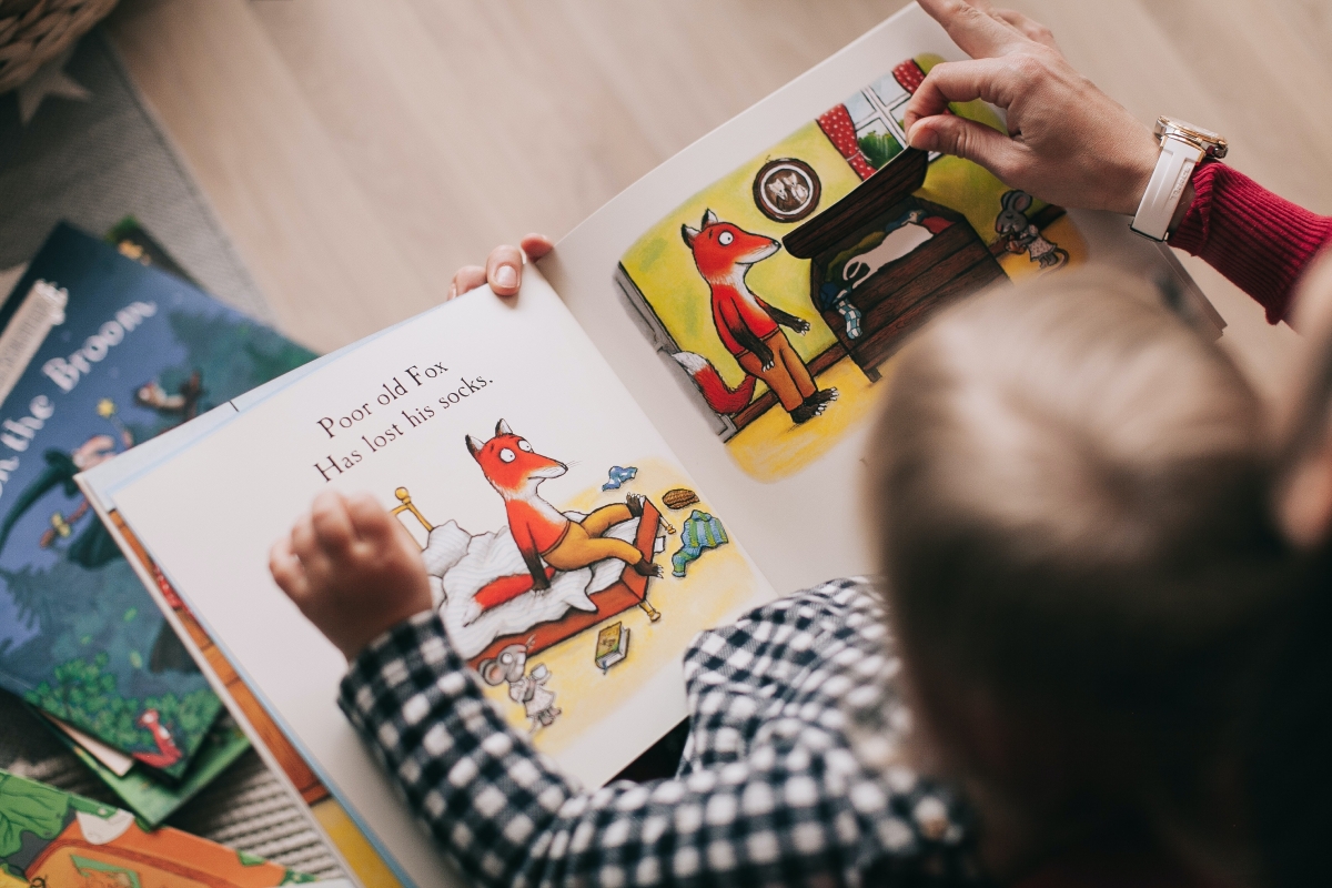 Baby sits with a daycare teacher reading a book together