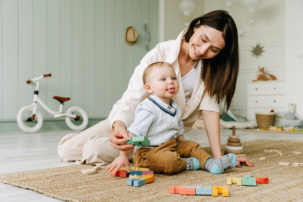 Daycare teacher plays with a baby on the floor