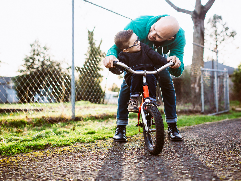 dad teaching child to ride a bike