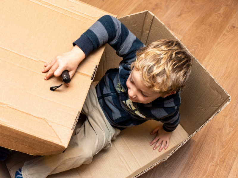 toddler playing in cardboard box