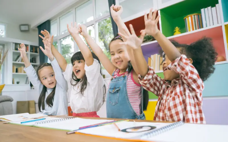 school children having fun in class, raising hands, diversity