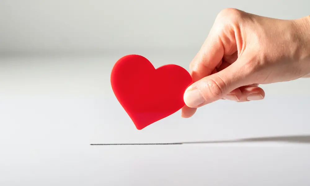 hand dropping paper heart in donation box, fundraiser