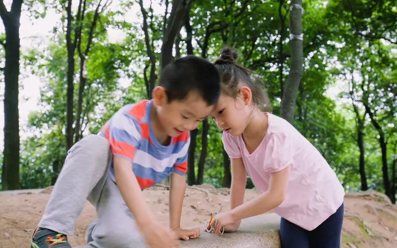 two asian children playing on a rock in the woods
