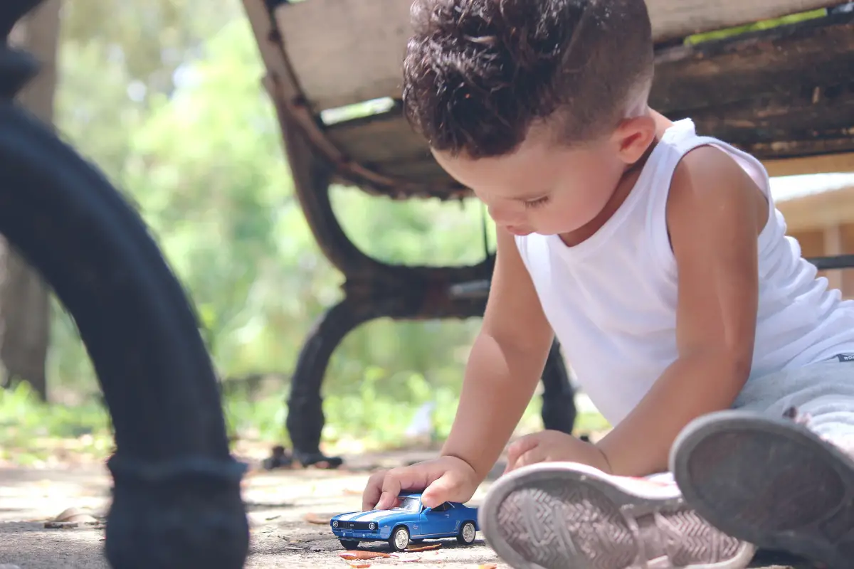 Young boy plays outside with a toy car.