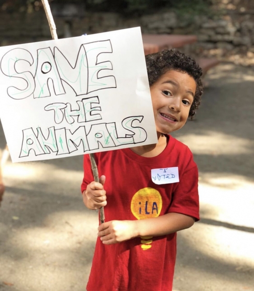 a child from inspired little activists preschool holds a sign to save the animals